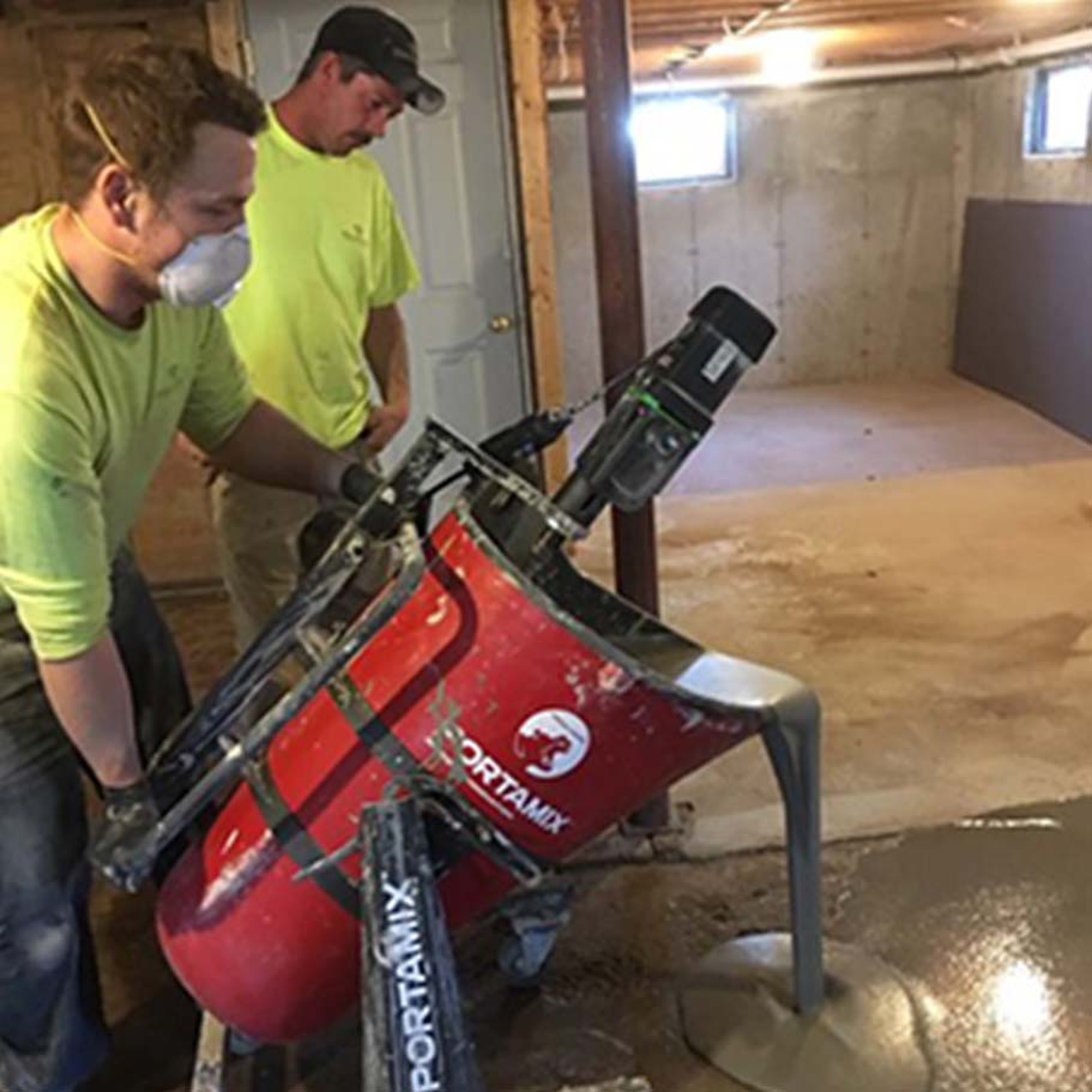 Crew pouring self-leveling compound from a Portamix Mega Hippo mixing station