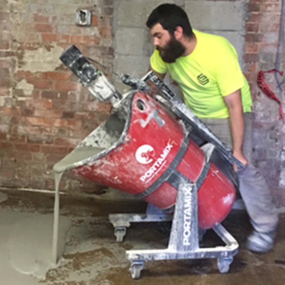 Worker tipping a Portamix Mega Hippo to pour self-leveler onto the floor
